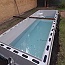 Prelivový obdĺžnikový bazén v šedej farbe s rohovými schodmi - usadený a v procese dopúšťania a obetónovávnia