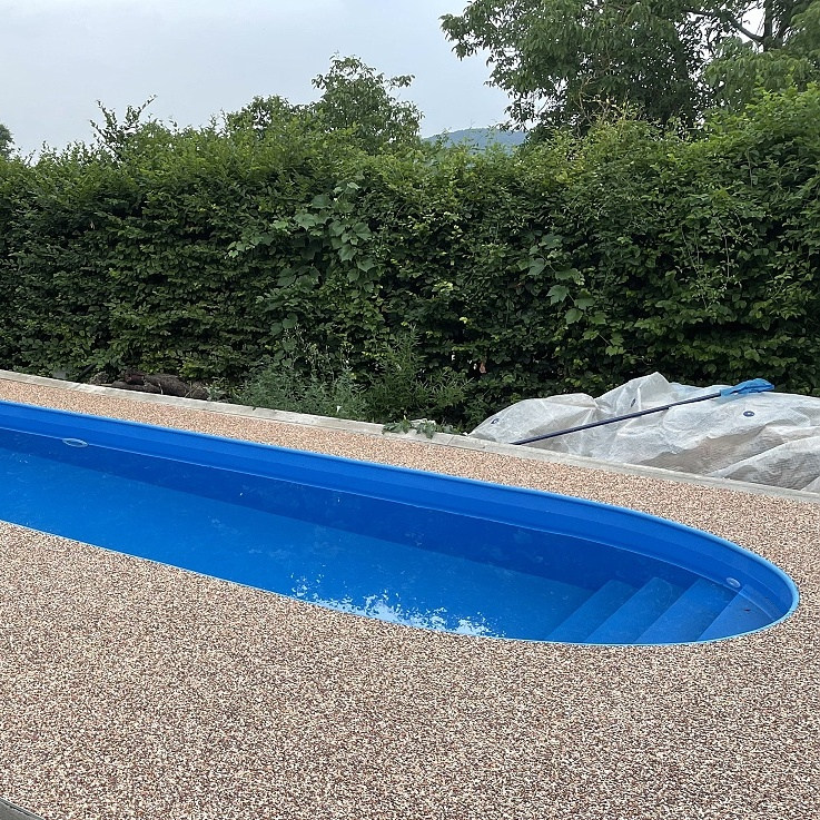 Oválny bazén v modrej farbe, schodisko cez celú šírku